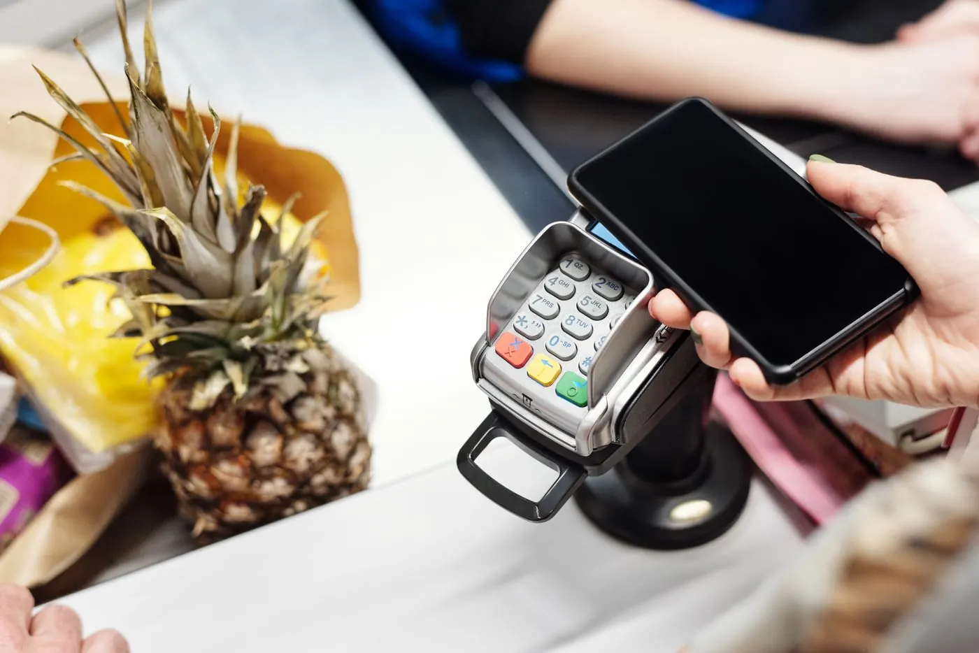 A customer paying by phone at a shop checkout