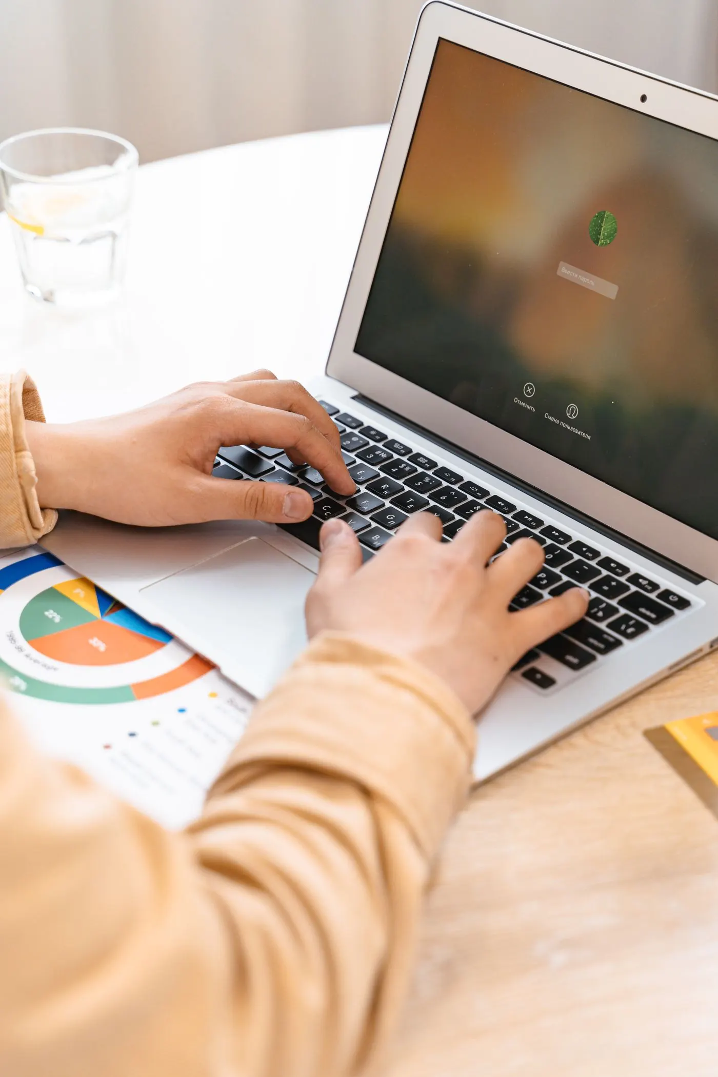 Hands typing on a laptop with charts on screen