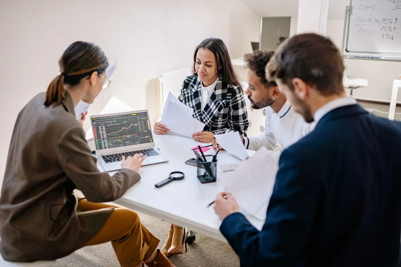 A team reviewing work on laptops in a meeting