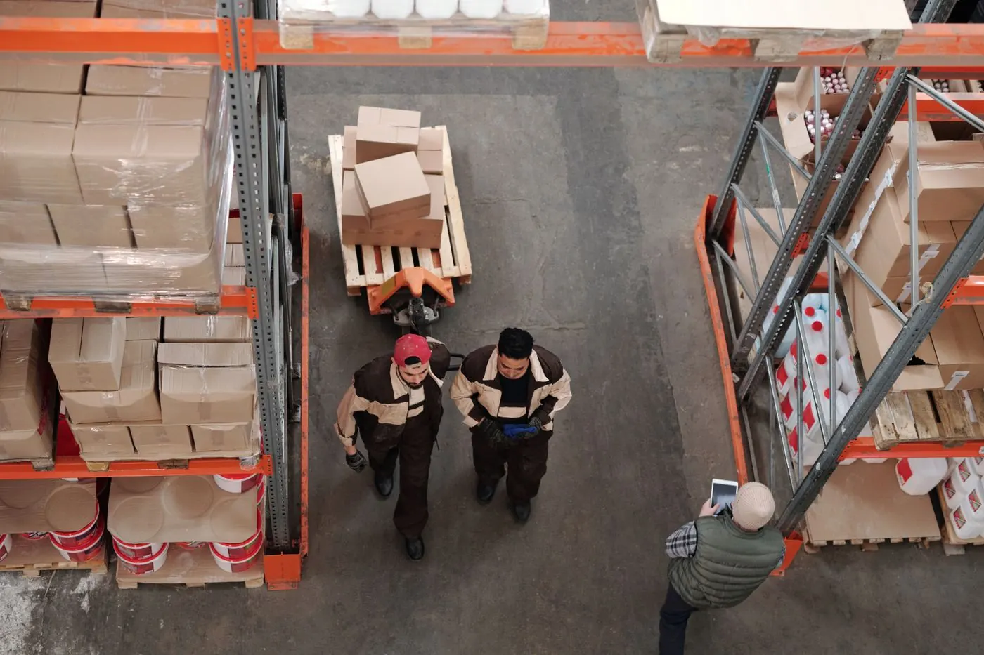 Workers moving stock between racks in a large warehouse